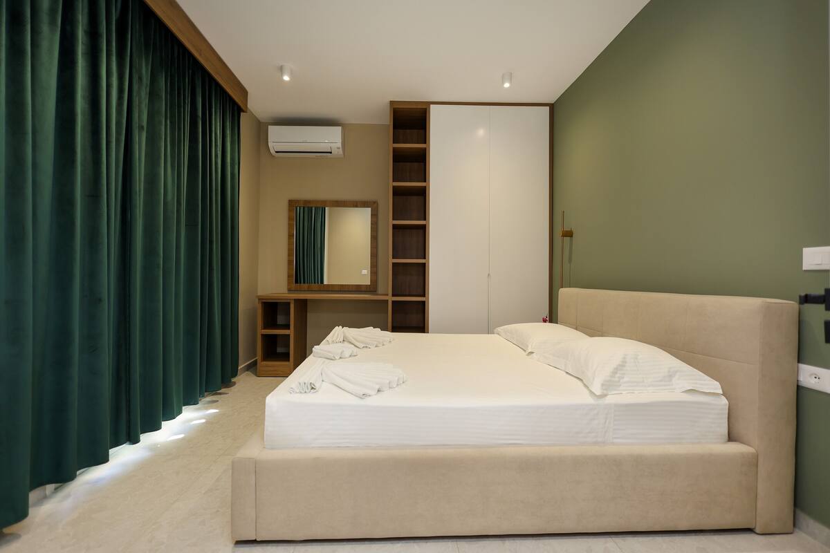 A modern bedroom with a large bed, built-in shelving, and a mirror.