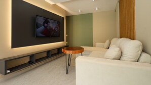 A modern living room with a flat-screen TV mounted on the wall, a white sofa, a wooden coffee table, and a minimalist design. - Apartments Luxury Mimani 2 (Velabisht)