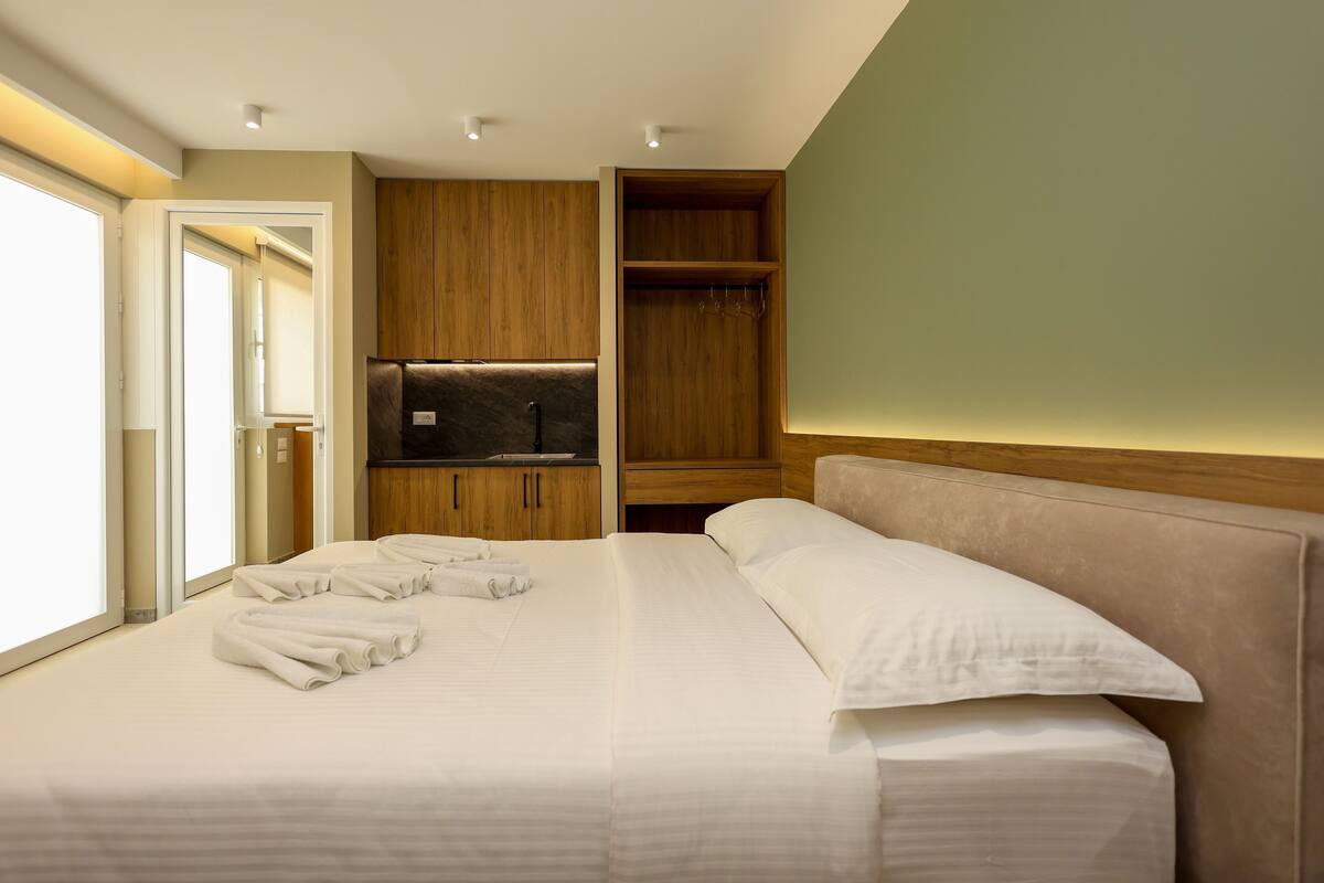A hotel room with a large bed, a wardrobe, a television, and a bathroom visible through an open door.