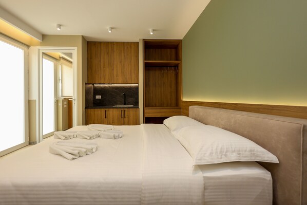 A hotel room with a large bed, a wardrobe, a television, and a bathroom visible through an open door.