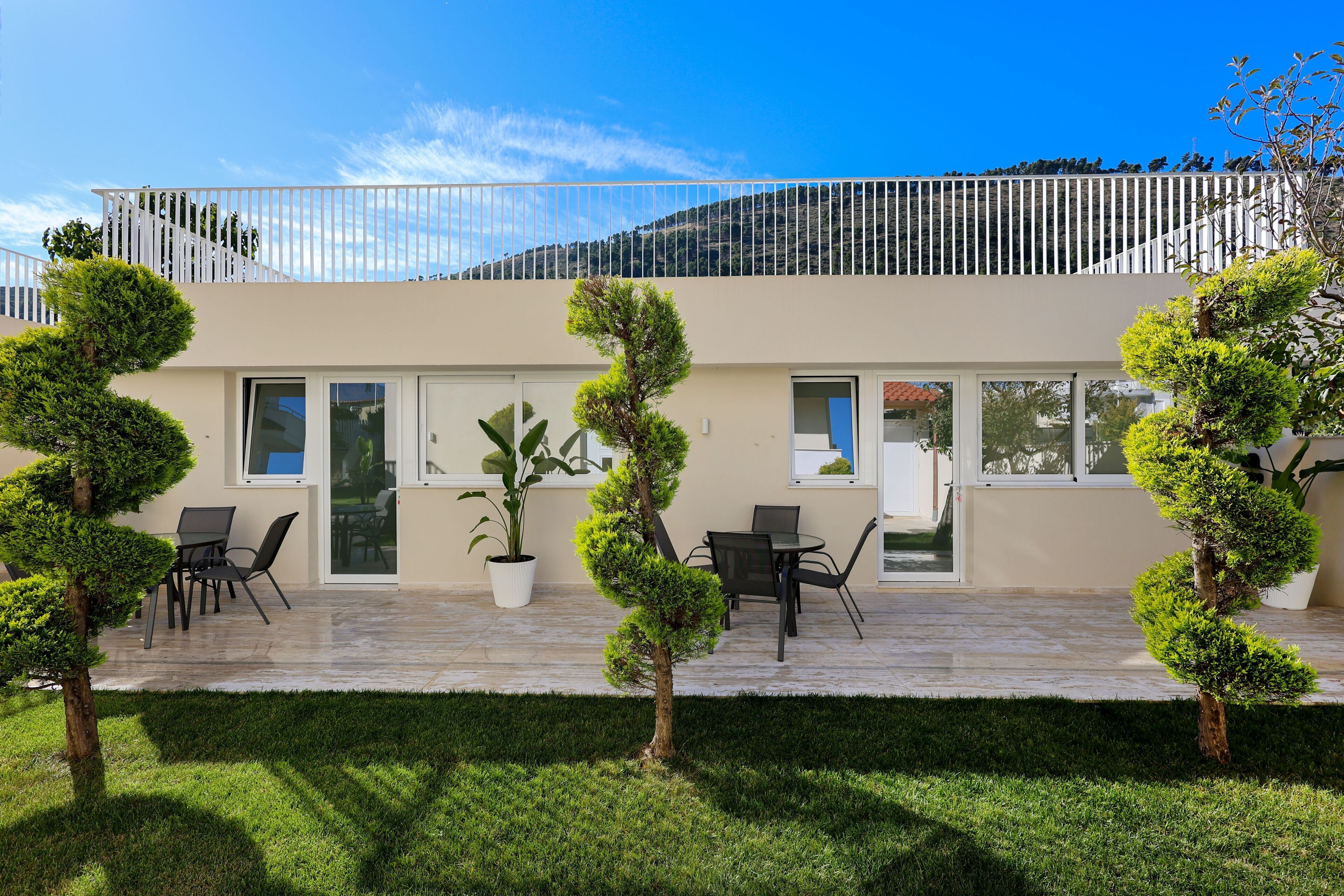 Un bâtiment moderne doté d’un balcon, de plantes en pot et d’un espace extérieur aménagé pour s’asseoir.