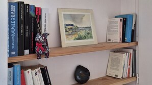 Une bibliothèque remplie de divers livres, un tableau encadré et des objets décoratifs.