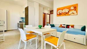 A modern kitchen with white cabinets, a dining table with chairs, and a sofa with colorful cushions. - Casa La Mamà, 150 meters from the sea (ALCAMO)