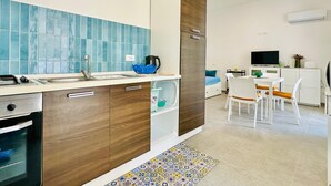 A modern kitchen with a built-in oven, a sink, and a coffee maker. There is a dining area with a table and chairs. - Casa La Mamà, 150 meters from the sea (ALCAMO)