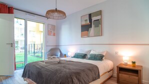 A bedroom with a bed, a chair, a nightstand, and a view of the outside. - Le Blue Dock - Port de Vannes (Vannes)