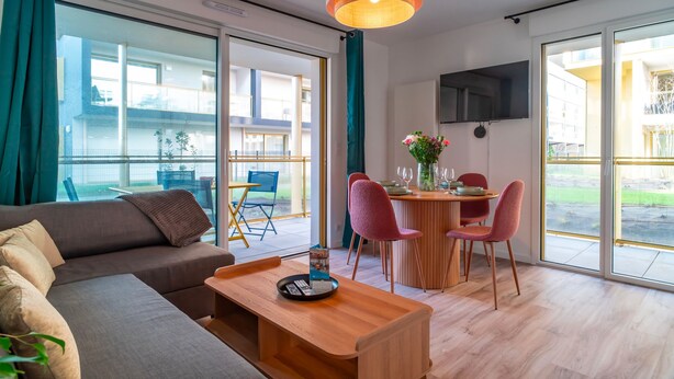 A modern living room with a sofa, a wooden coffee table, and a dining area with a table and chairs. - Le Blue Dock - Port de Vannes (Vannes)