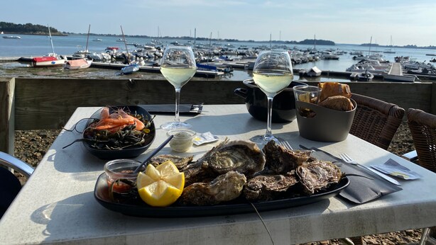 A table with seafood, two glasses of white wine, and bread by a waterfront view. - Les Voiles Arradonnaises - Proche sentier côtier (Arradon)
