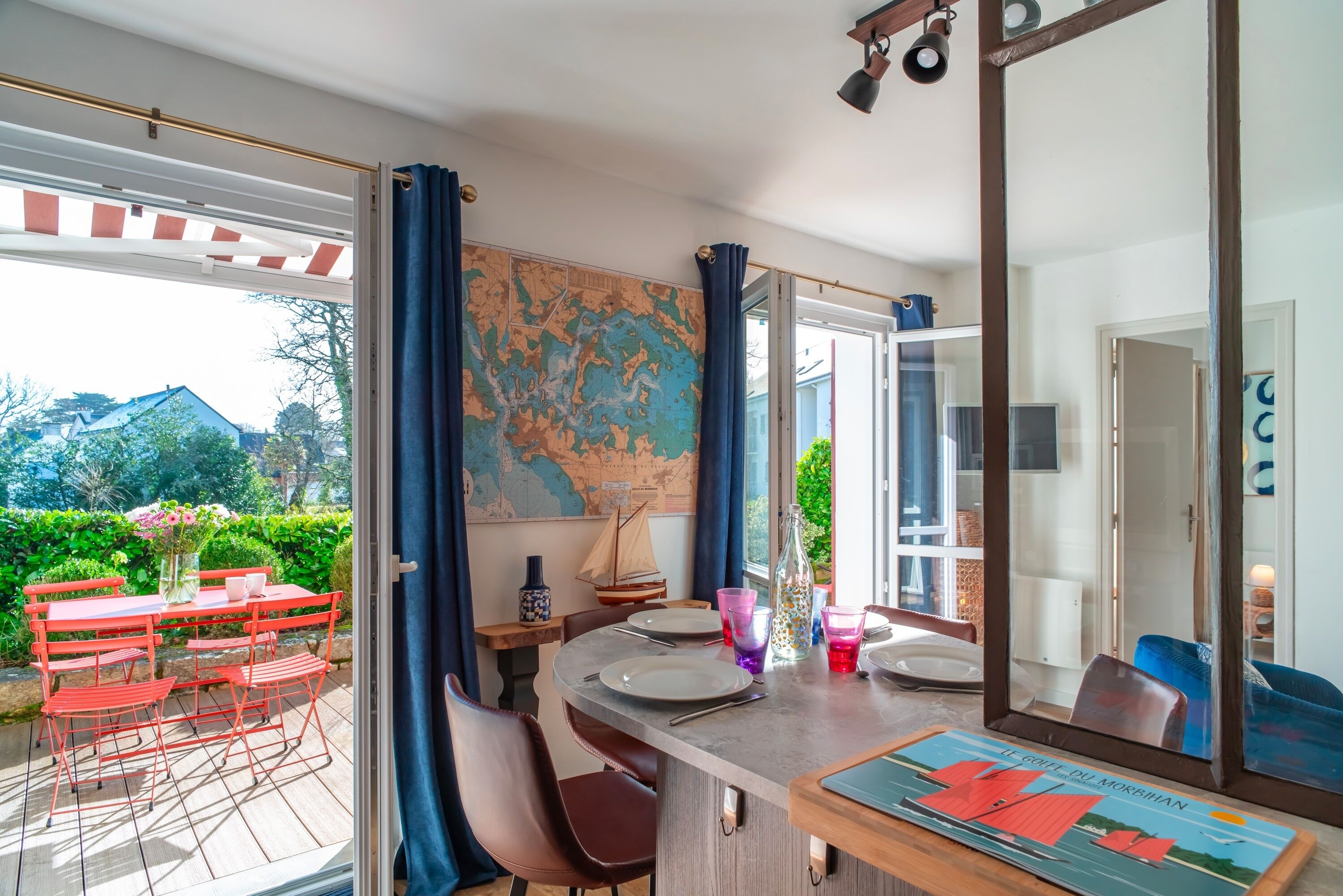 A dining area with a table set for two, a map on the wall, and a view of the outdoors.