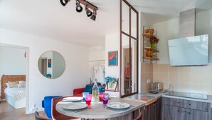A modern kitchen with a dining area, a bed, and a large mirror. - Les Voiles Arradonnaises - Proche sentier côtier (Arradon)