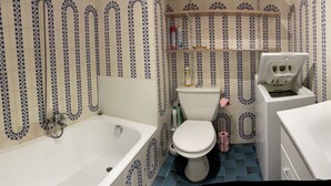 A bathroom with a bathtub, toilet, and sink, all with matching blue and white patterned tiles.