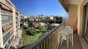 A balcony with a view of a residential area, a white plastic table, and a red bucket.