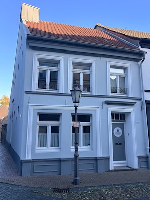 A two-story building with a traditional facade, a tiled roof, and a street lamp in front.