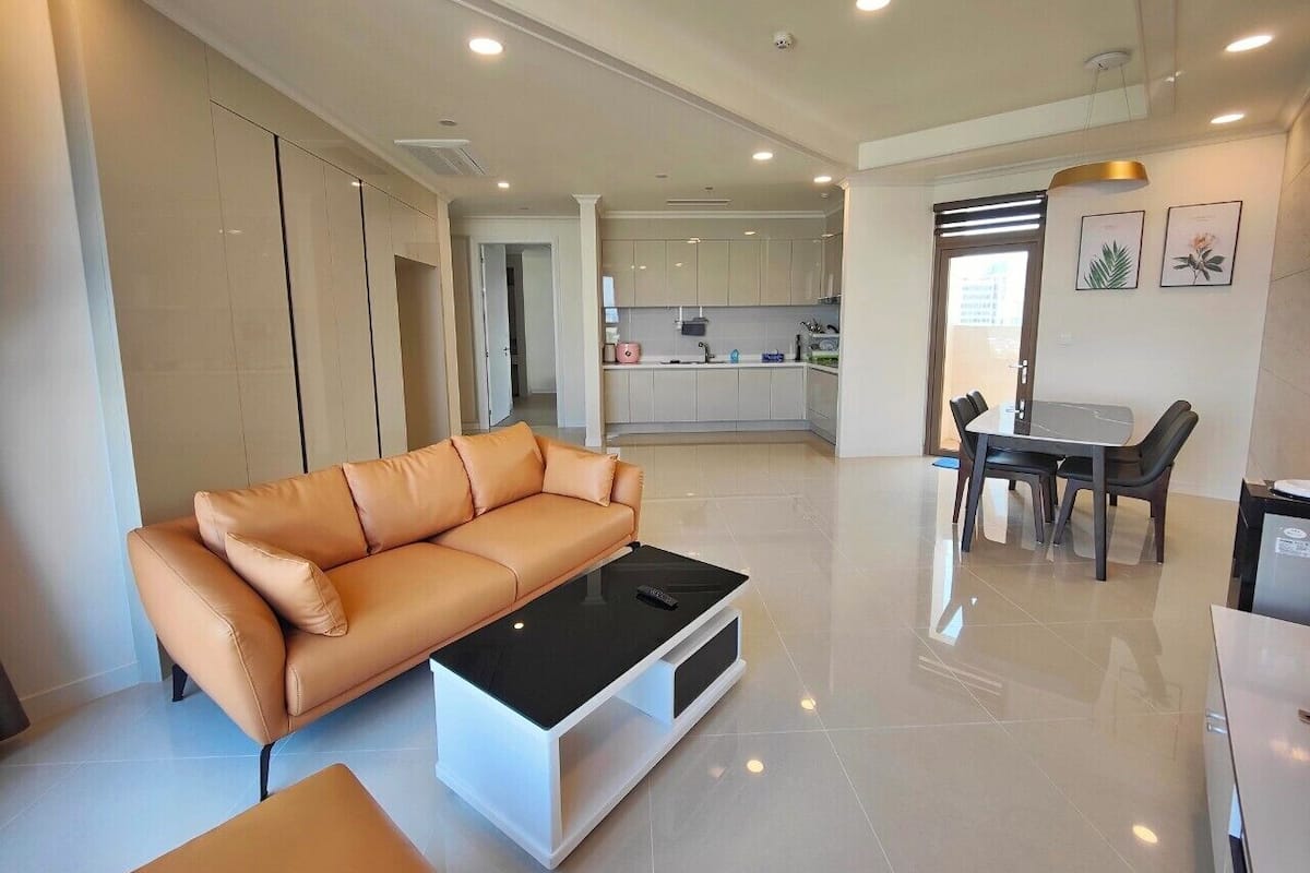 A modern living room with a leather sofa, a coffee table, and a dining area with a table and chairs.