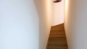 Una escalera de madera con paredes blancas y un accesorio de iluminación en la parte superior.