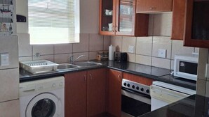 Une cuisine compacte équipée d’un lave-linge, d’un four à micro-ondes et d’une cuisinière.