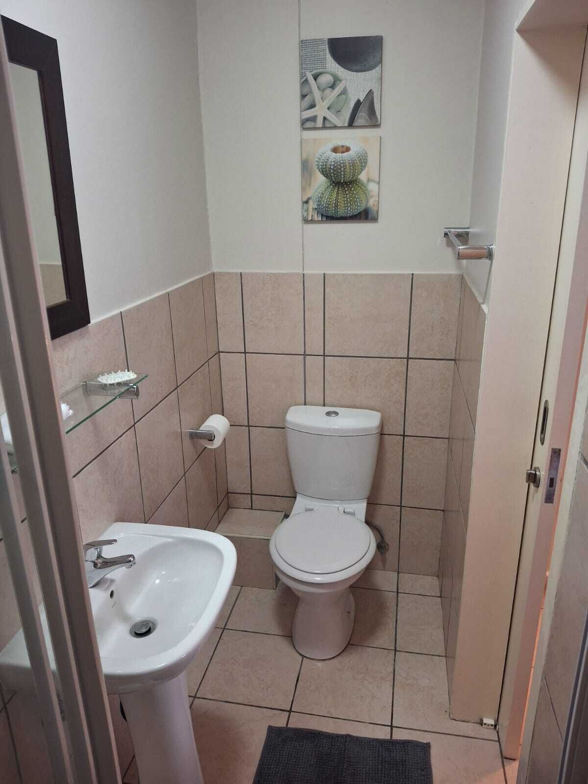 A small bathroom with a toilet, sink, and a mirror.
