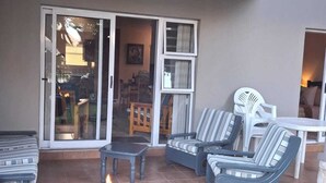 Une terrasse extérieure équipée d’un barbecue, de mobilier de jardin et d’une porte-fenêtre coulissante donnant sur un espace intérieur.