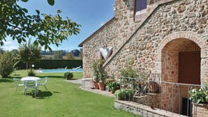 Un bâtiment en pierre doté d’une piscine, d’une pelouse et de mobilier d’extérieur.