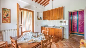 Un coin repas avec une table en bois dressée pour deux personnes, une cuisine avec des placards en bois et une porte aux couleurs vives.