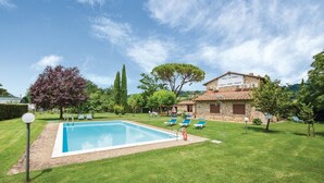 Une piscine avec des chaises longues, un bâtiment en pierre portant l’inscription « Casa Vacanze », et une pelouse verdoyante avec des arbres.
