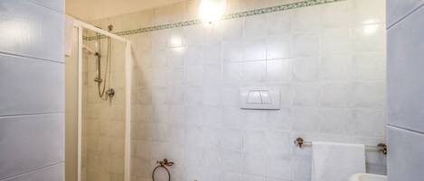 Et badeværelse med bruser, pissoir og håndvask.
