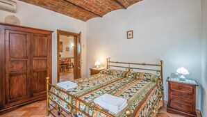 Une chambre à coucher avec un lit en bois, une table de chevet avec une lampe, une armoire et un plafond en briques.