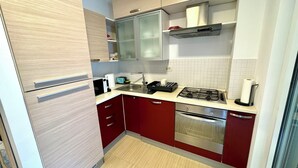 Cocina compacta con refrigerador, microondas, estufa, horno y pileta.
