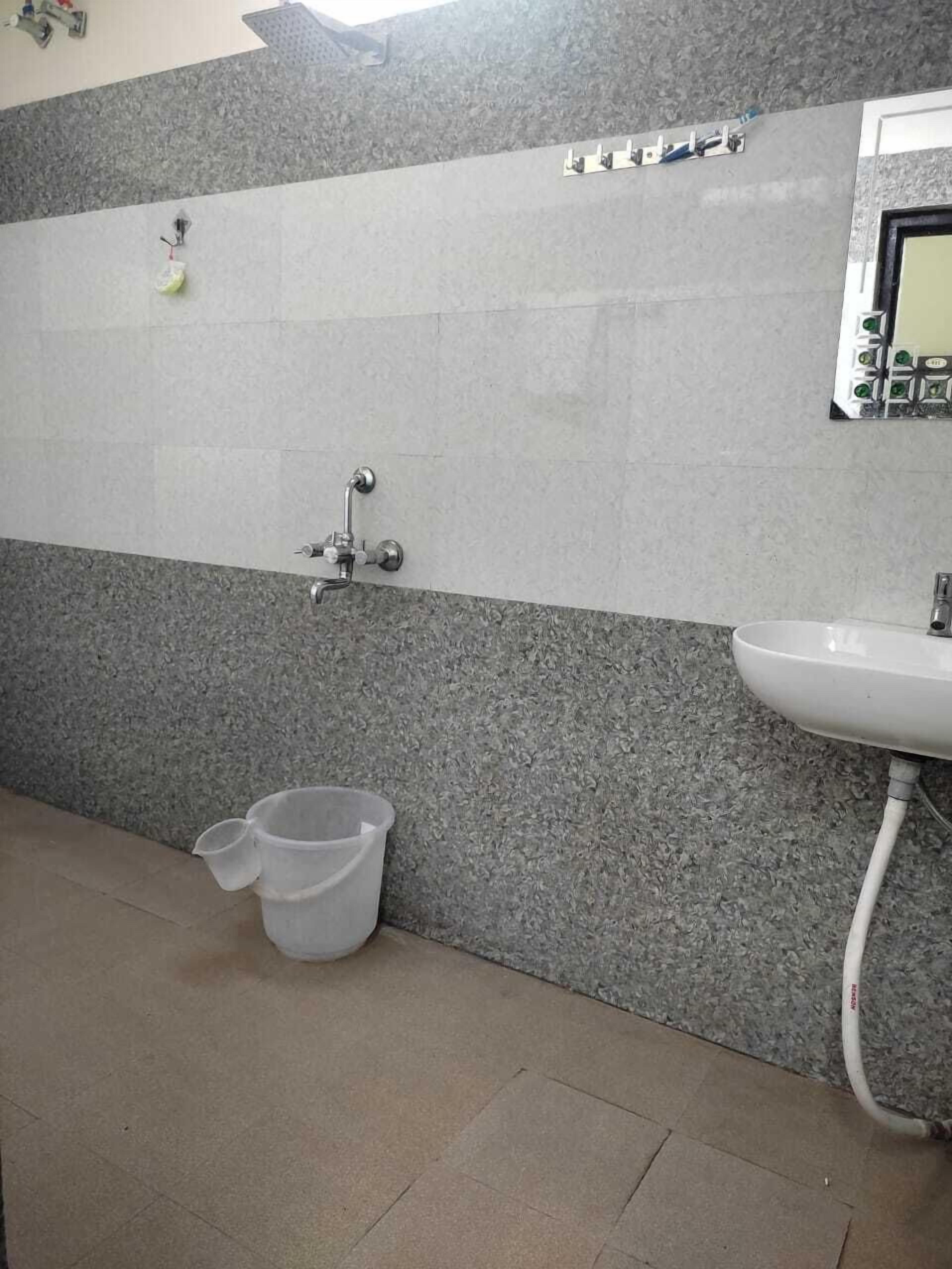 Een badkamer met een wastafel, douche en betegelde muur.