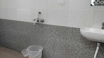 Een badkamer met een wastafel, douche en betegelde muur.