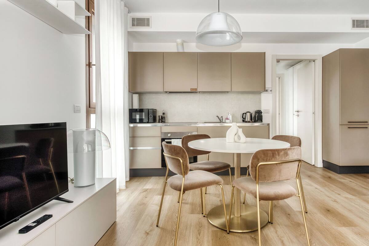 Une cuisine moderne avec un coin repas, un téléviseur et une machine à café.