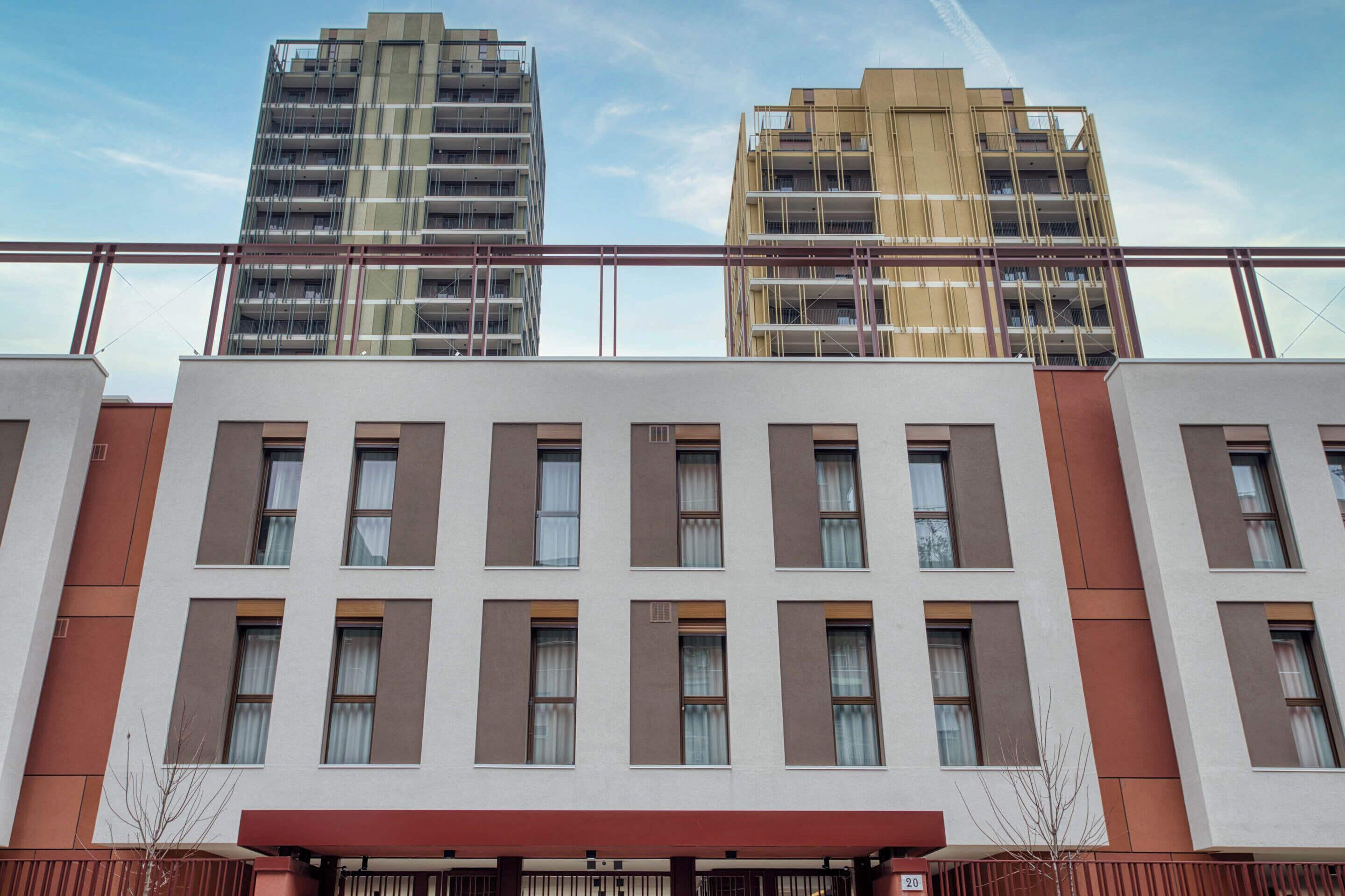 A multi-story building with a modern architectural design, featuring a series of windows and a red awning.