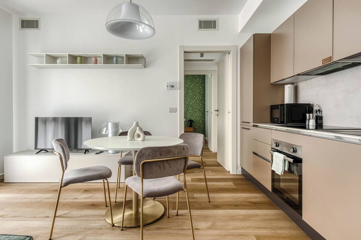 Une cuisine moderne avec une table de salle à manger ronde, des chaises et un four encastré.