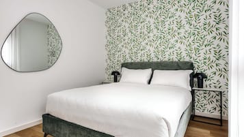 Un letto con una testiera verde, biancheria da letto bianca e una parete con un motivo a foglie.