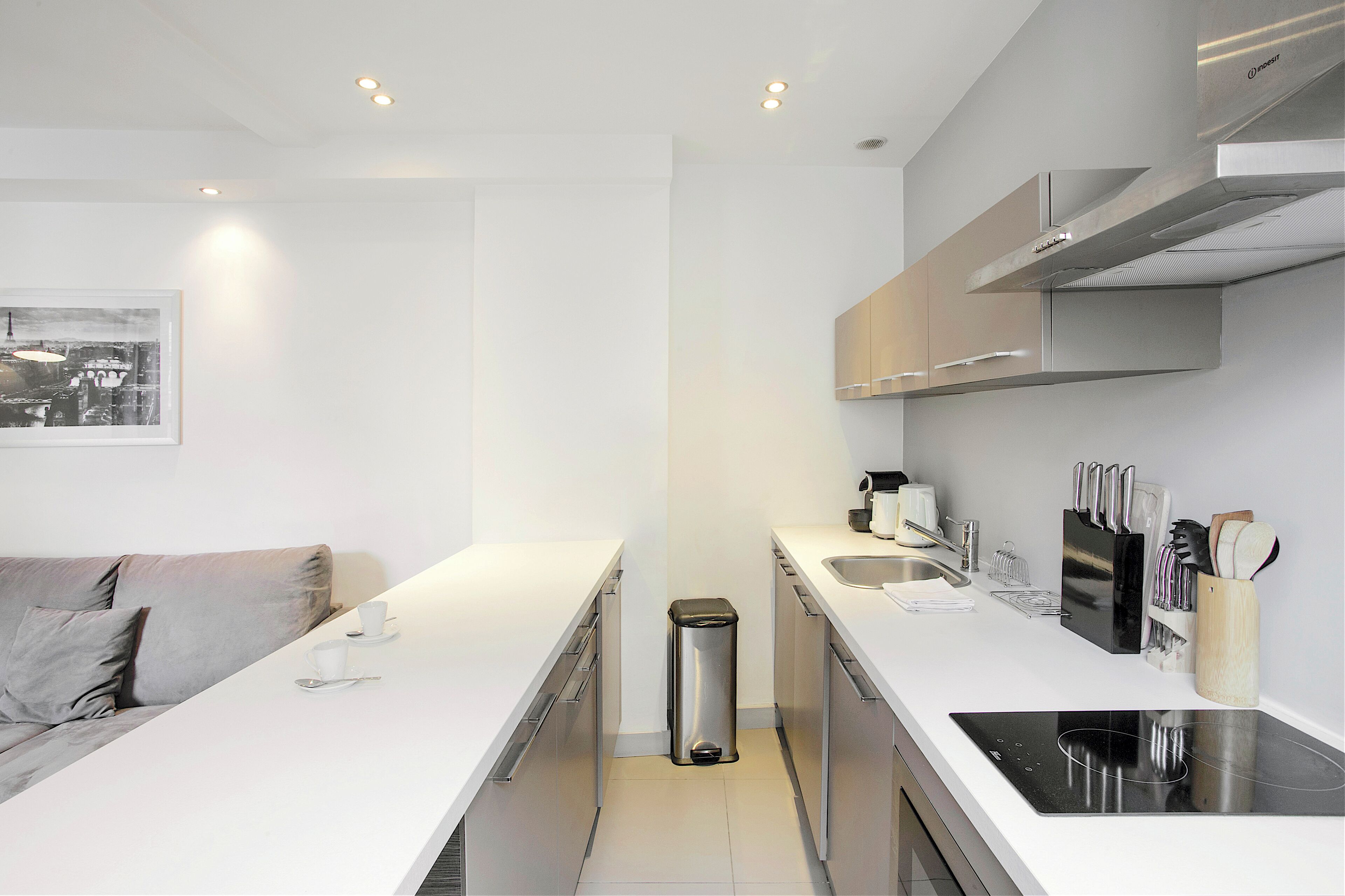 A modern kitchen with a white countertop, stainless steel appliances, and a black induction cooktop.