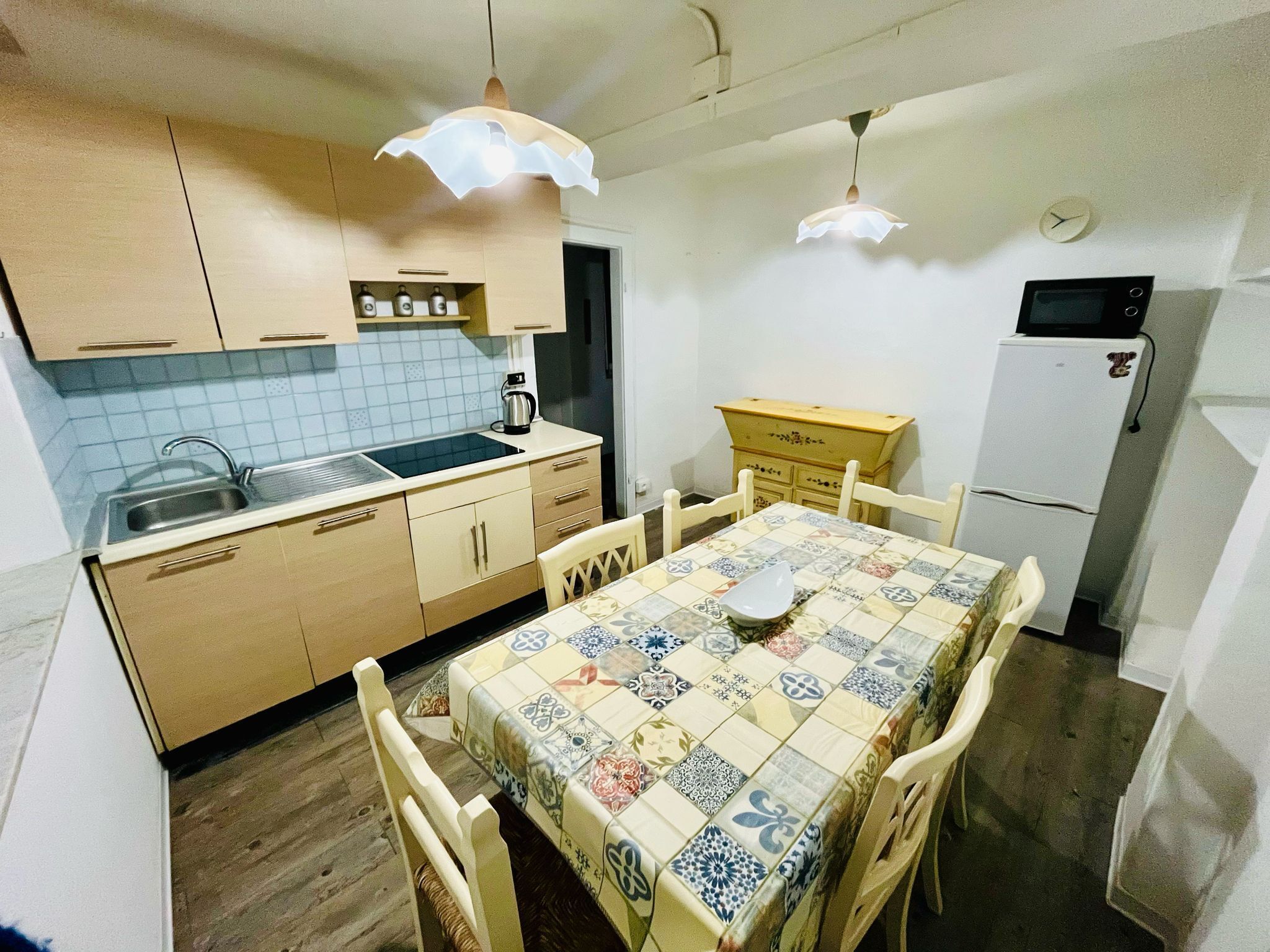 A compact kitchen with a tiled backsplash, a sink, a stove, and a refrigerator.