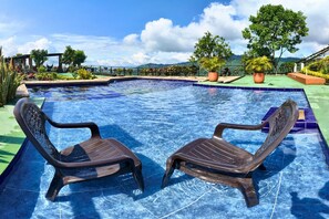 Una piscina con dos sillas y plantas en macetas alrededor.