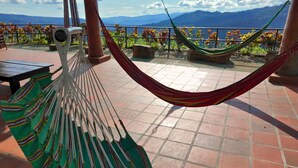 Una hamaca en un patio con baldosas y vistas a la montaña.