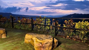 Un jardín de rocas con vistas a montañas y un lago al atardecer.