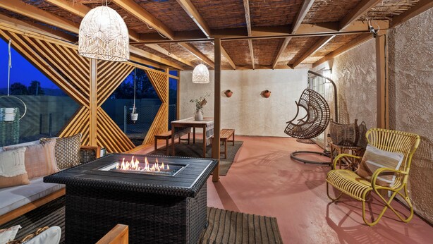 A cozy outdoor seating area with a fire pit, wicker furniture, and a hanging chair. - Desert escape w/ hot tub, pool, fire pit & fully fenced yard — 15 min to JTNP. Perfect for dog-friendly getaways. 🌵✨ (Joshua Tree)