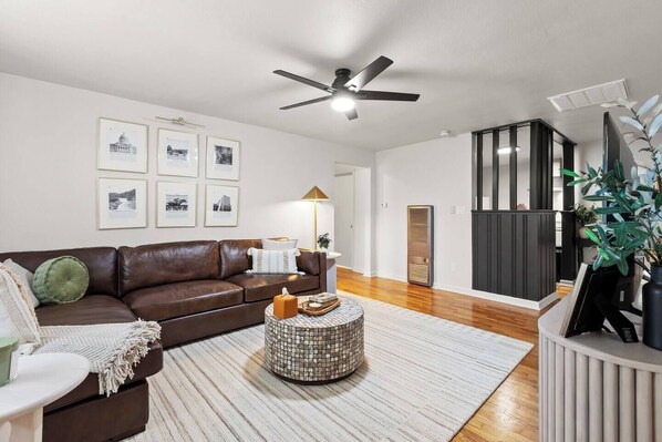A modern living room with a brown leather sofa, a round woven coffee table, and framed pictures on the wall. - This apartment is a 2 bedroom(s), 1 bathrooms, located in Frankfort, KY. (Frankfort)