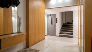 A hallway with wooden paneling, a mirror, a small statue, and a staircase leading to another room. - Athens Panorama Penthouse by the Acropolis (Athina)
