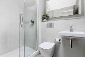 Une salle de bain avec une douche Ă parois en verre, des toilettes et un lavabo.