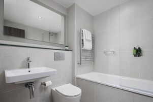 A modern bathroom with a white sink, toilet, and bathtub.