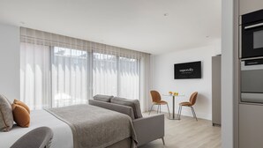 A modern hotel room with a large bed, a small sofa, a dining area with two chairs, and a TV on the wall. - Forth House by Supercity Aparthotels (Edinburgh)