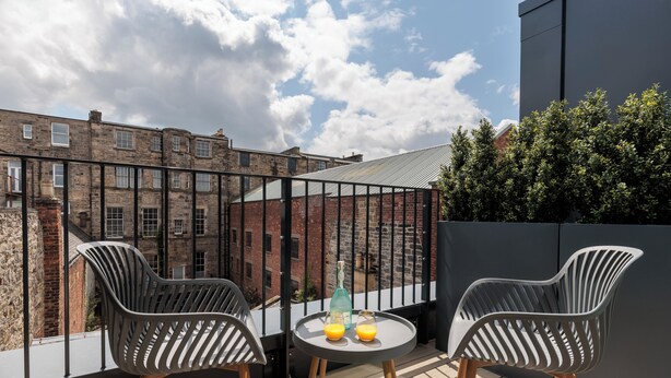 A balcony with two modern chairs, a small table, and two glasses of orange juice. - Forth House by Supercity Aparthotels (Edinburgh)