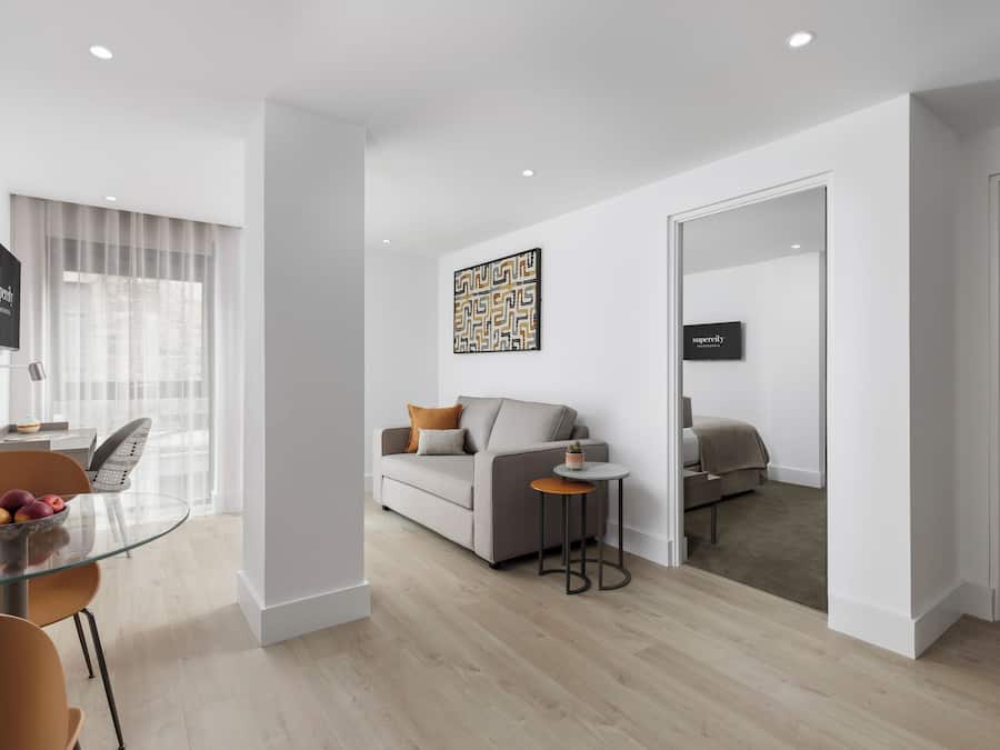 A modern living room with a sofa, a glass dining table, and a small side table.