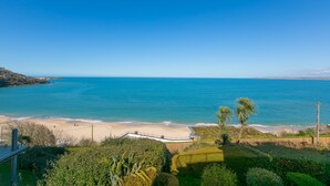 A coastal view with a beach, clear sky, and lush greenery.