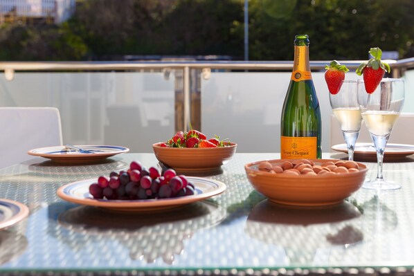 Ein Tisch ist gedeckt mit Trauben, Erdbeeren, einer Champagnerflasche, Gläsern und einer Schale Kekse.