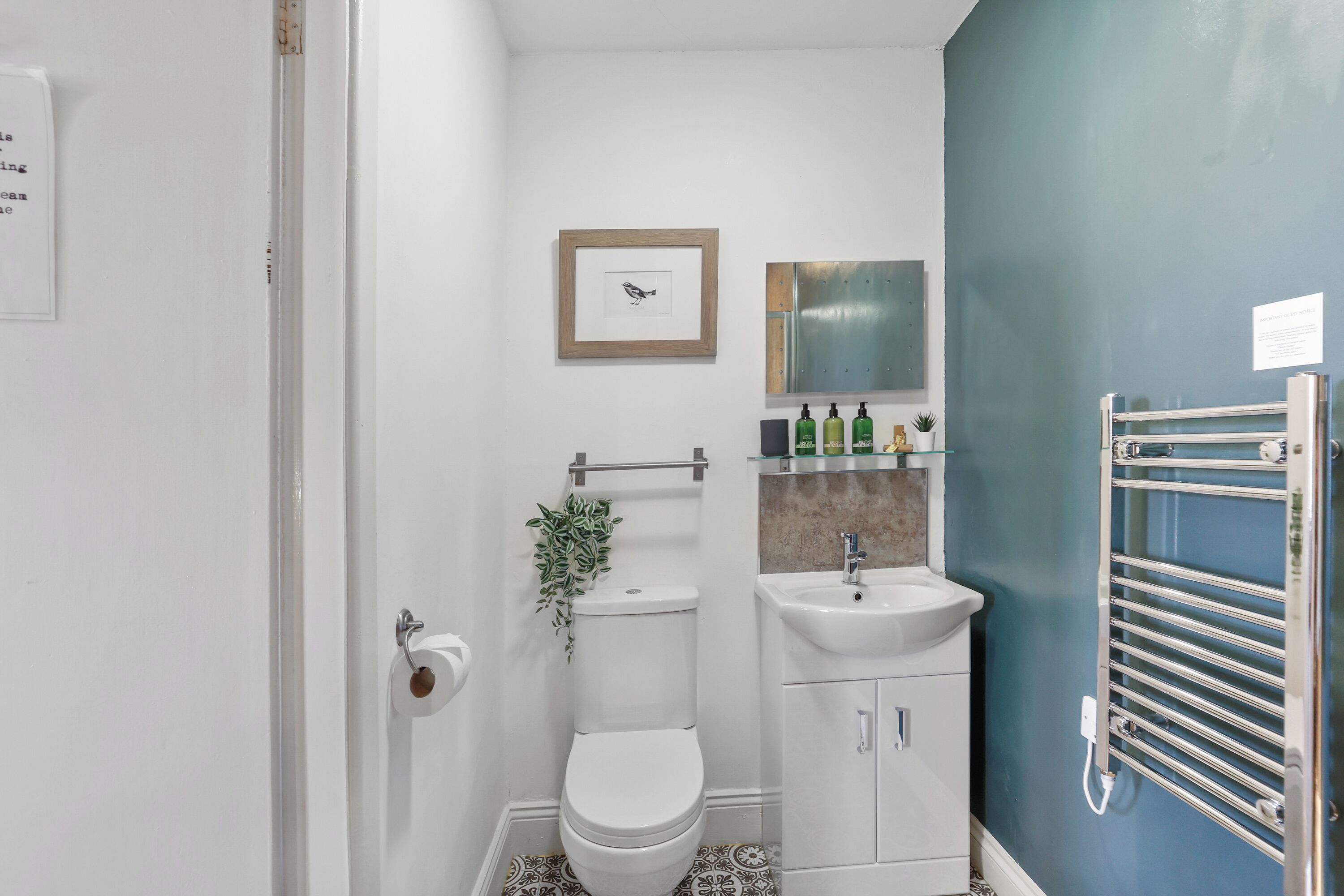 A compact bathroom with a toilet, sink, and towel rack.