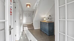 A hallway with a staircase, a blue cabinet, and a door with a handle. - Wyndgrove House - North East Escapes (Seahouses)